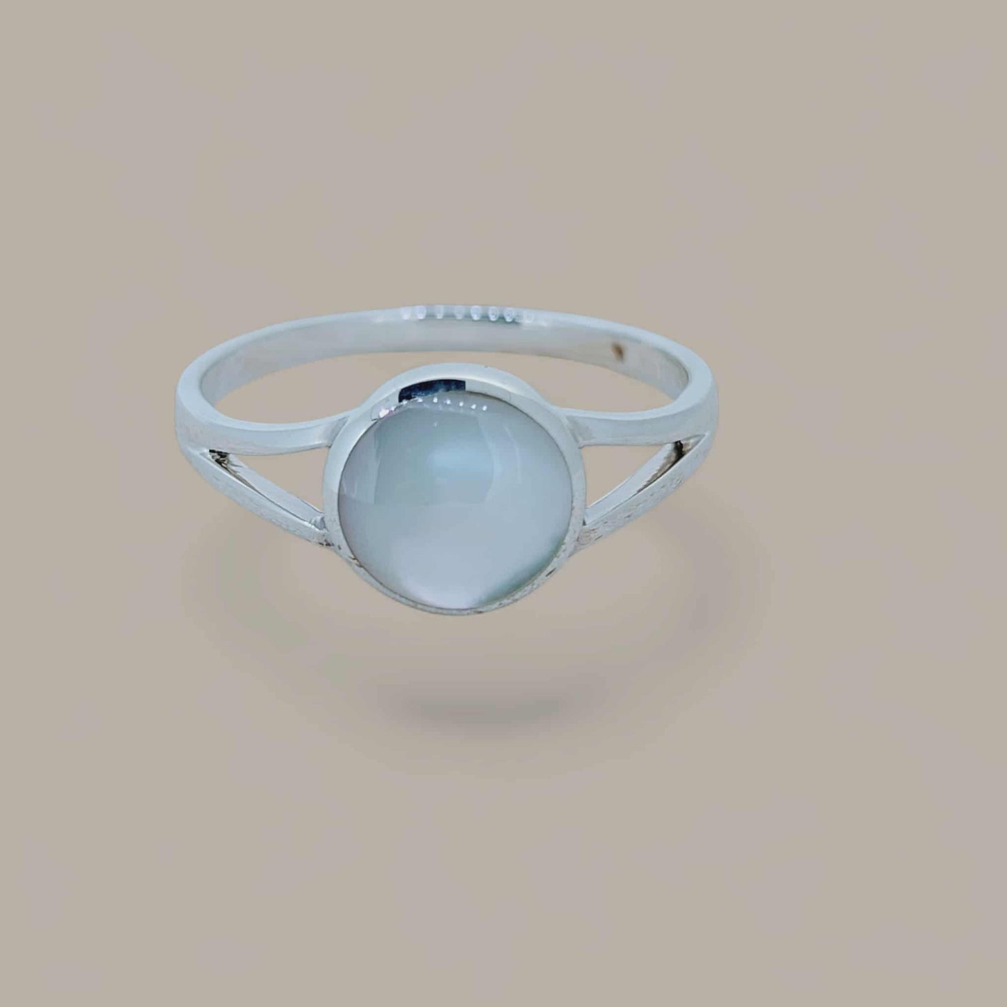 Mother of Pearl cabochon is encircled by a smooth “pond” of silver in this gentle split band ring