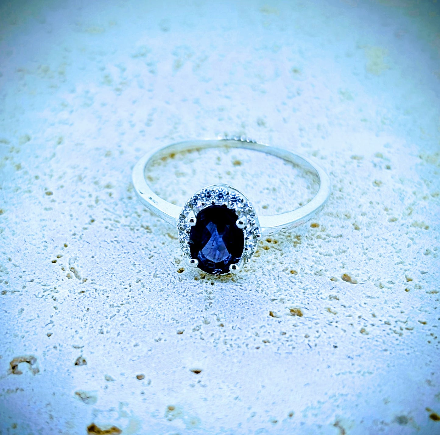 This iolite gem is nestled among white zircons with each one claw-set in this sterling silver ring