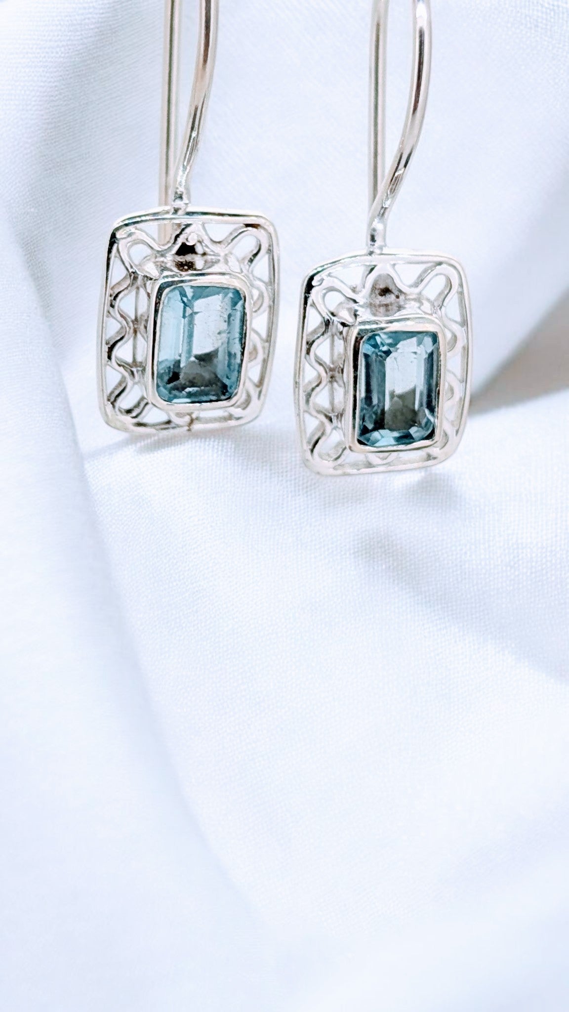 Intricate silver webbing forms a delicately framing for a vivid blue topaz gemstone