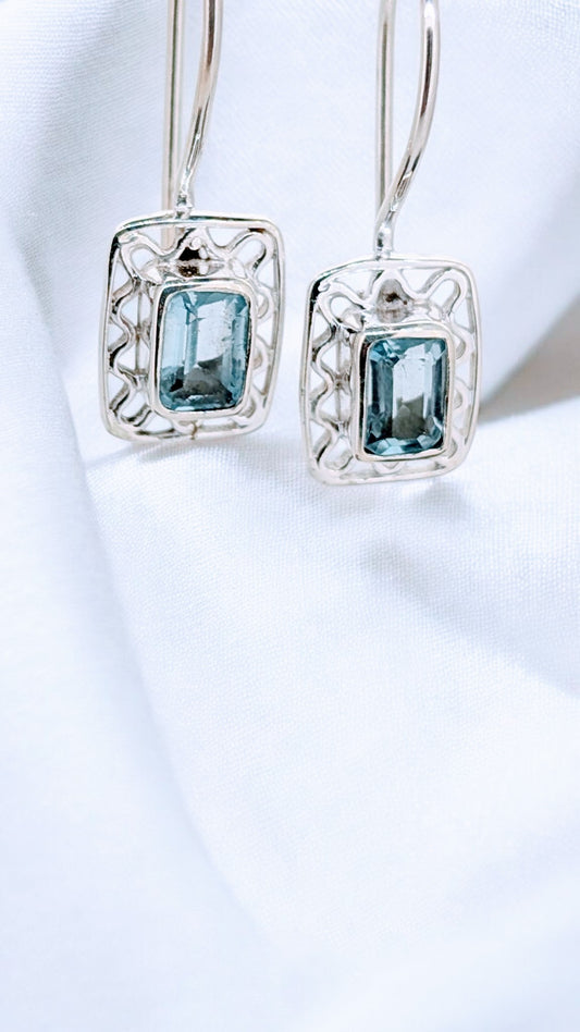 Intricate silver webbing forms a delicately framing for a vivid blue topaz gemstone